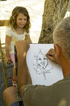 Caricature artist drawing young girl