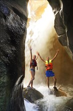 Young couple under waterfall at the canyon of Wadi Mujib