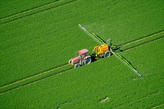 Tracker spraying pesticides on a green grain field