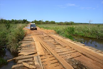 All-terrain vehicle crosses simple wooden bridge