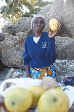 Female fruit vendor holding mango in her hand