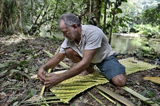 Man weaving palm leaf sunshade