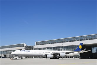 Lufthansa Airbus A340 with push-back truck in front of maintenance hangar