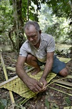 Man weaving palm leaf sunshade