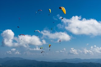 Many paragliders are flying over Pokhara and Phewa Lake
