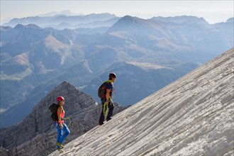 Mountain guide guiding a young woman on a short rope through a rock face