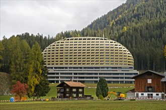 Old Swiss farmhouse in front of modern InterContinental Davos Hotel