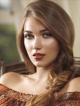 Portrait of a young beautiful woman with long light brown braided hair sitting in a chair