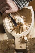 Carving the backside of a wooden mask using wood carving tools