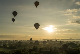 Hot air balloons at sunrise over temples and pagodas