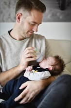 Young father feeding infant