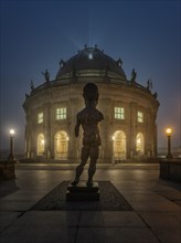 Bodemuseum on the Museum Island with the bronze sculpture Hektor by Markus Lupertz at fog in dusk
