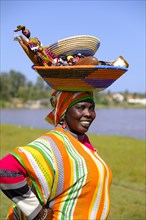 Senegalese woman in colorful dress with goods on her head