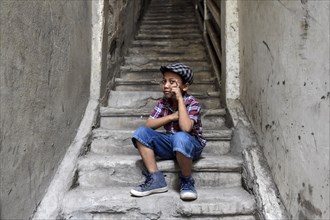 Boy on staircase with shirt and flat cap