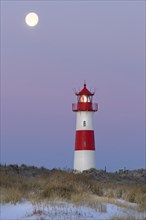 Red and white striped lighthouse List East in the dunes at the full moon