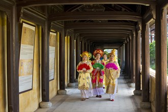 Vietnamese extras in traditional robes walking through imperial palace Hoang Thanh
