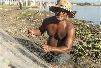 Fisherman mending his net Taungthaman Lake