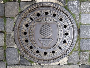 Cast iron ore manhole cover engraved with stone pine and Augsburg coat of arms