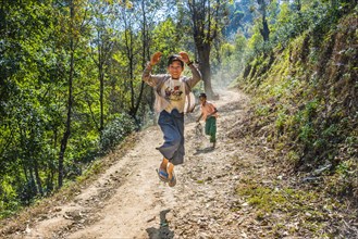 Boy jumping happily on dirt road