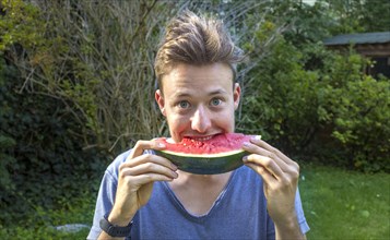 Young man eating a melon