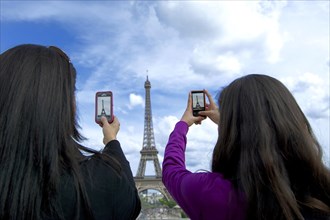Tourists photographing Eiffel tower with his smartphone