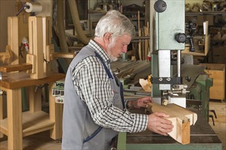 Wooden mask carver cutting a wooden block using a band saw