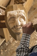 Carving the mouth of a wooden mask using wood carving tools