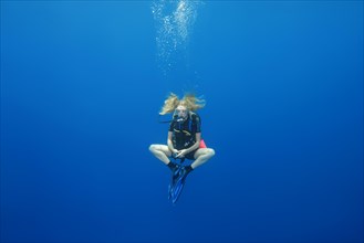 Female scuba diver hung in a lotus pose for a safety stop