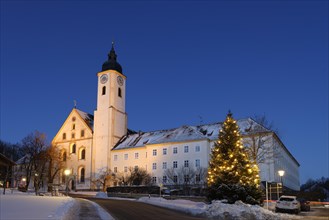Illuminated Christmas tree in front of monastery church Dietramszell