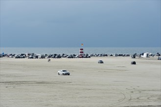 Cars parked on wide sandy beach