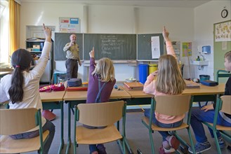 Students in elementary school with raised hands in classroom