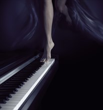 Woman bare legs dancing on a piano keyboard
