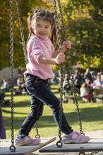 Eurasian girl standing on swing