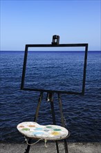 Easel and pallet in front of the sea