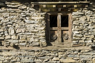 Wooden paneled window of an old stone house