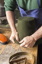 Man fitting wet hat body to wooden form
