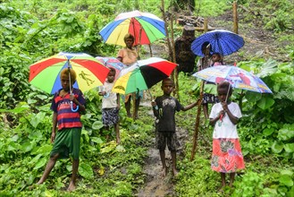 Native women with children with colourful umbrellas in the rain in the village of Rangsuksuk