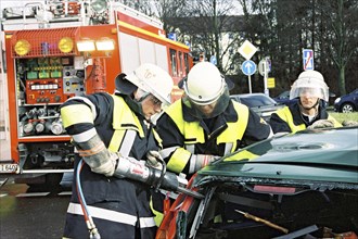 Firemen at traffic accident using Jaws of Life to rescue trapped car driver