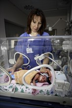 Nurse at incubator with newborn baby