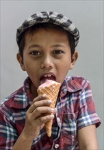 Boy with shirt and flat cap eating ice cream