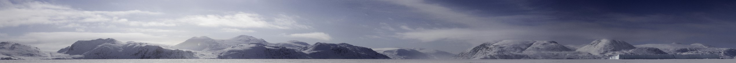 Panoramic view of snow-covered mountains seen from a frozen fjord