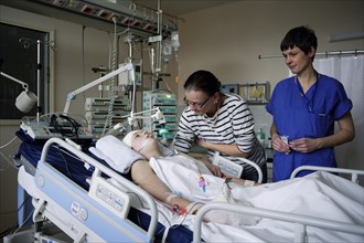 Child with mother and intensive care nurse at the bedside