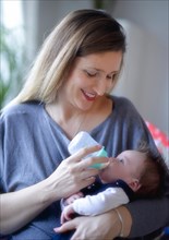 Mother feeds baby with baby bottle