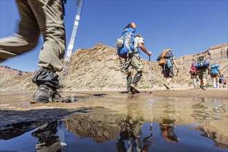 Hikers with backpacks crossing Fish River