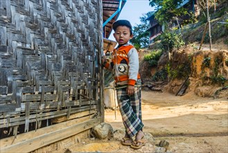 Little boy stands in front of log cabin