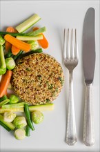 Quinoa burger with vegetables and cutlery