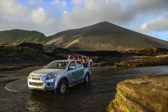 Jeep crosses river below volcano Yasur