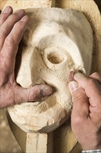 Sanding the face of a wooden mask