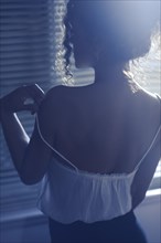 Back of a sexy woman undressing by the window