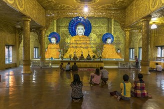 Religous people praying in front of Buddha statues Shwemokhtaw Pagoda
